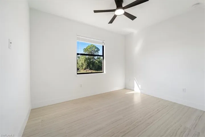 Empty room featuring baseboards, light wood-style flooring, and a ceiling fan