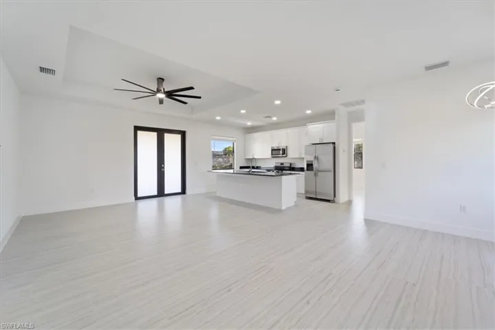 Unfurnished living room with baseboards, a tray ceiling, visible vents, and french doors