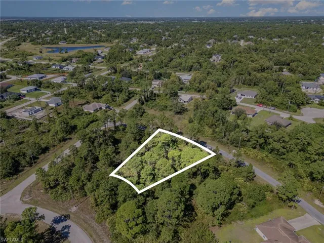 Aerial view of property and surrounding area with property parcel outlined and a large body of water