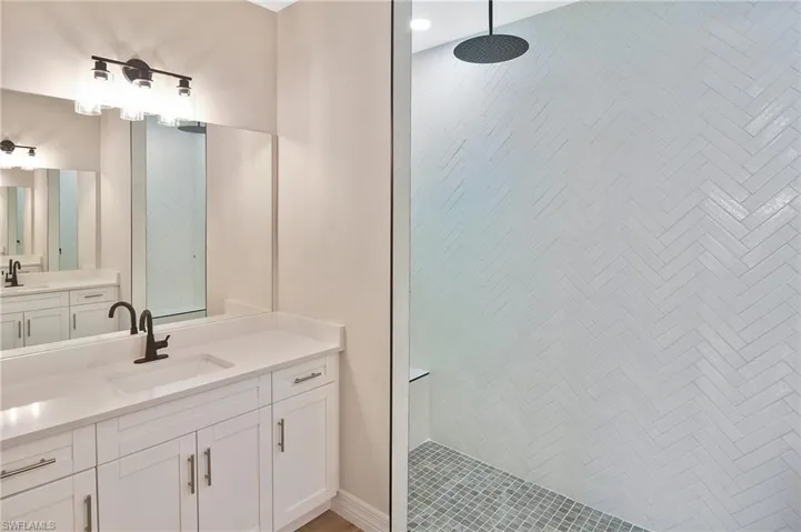 Modern bathroom featuring a white vanity with integrated sink, matte black faucet, and a large mirror
