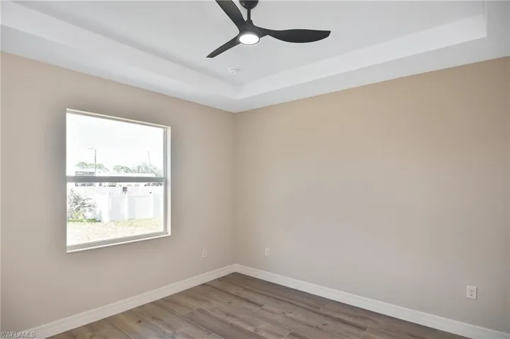 Wood-finish flooring and tray ceiling featuring a modern ceiling fan