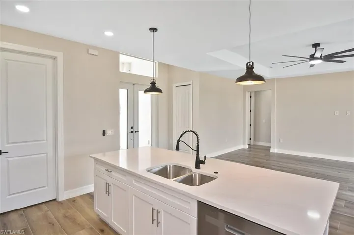 Kitchen island featuring a double-basin sink, gooseneck faucet, and integrated dishwasher