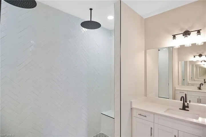 Walk-in shower with herringbone tile, dual rainfall showerheads, and a built-in bench