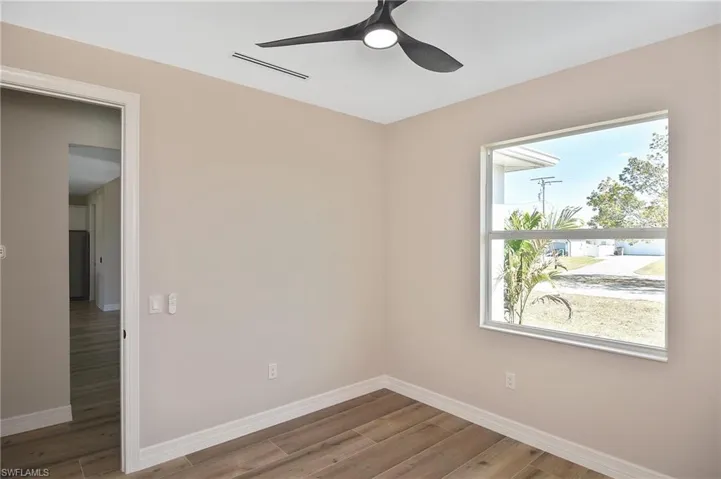 Neutral-toned room featuring wood-finish flooring and white baseboards