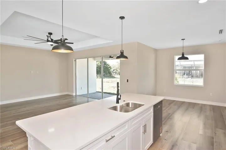Kitchen island featuring a double basin stainless steel sink with a matte black faucet, and white cabinetry