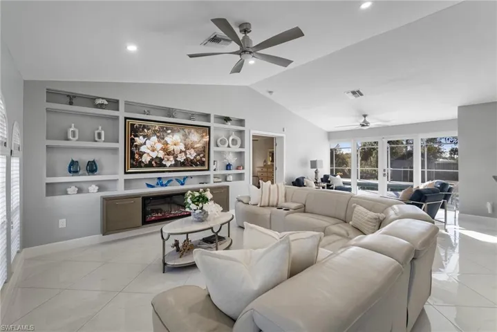 Living room featuring french doors, vaulted ceiling, built in shelves, ceiling fan, and light tile patterned floors