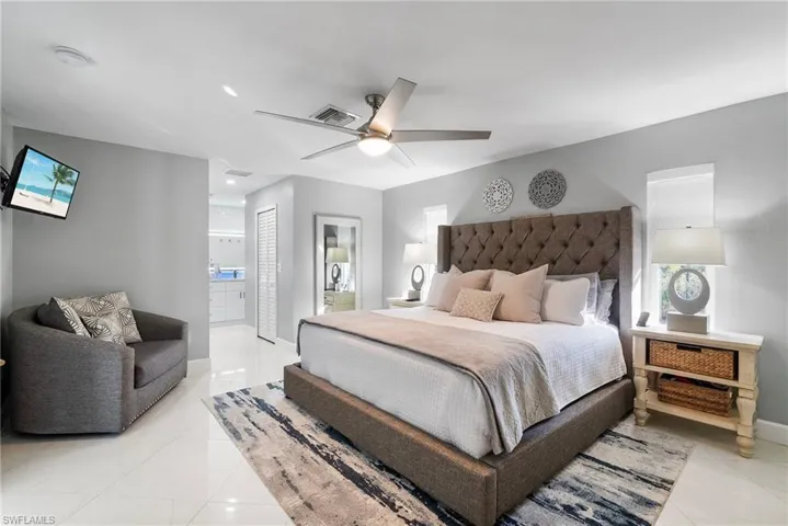 Tiled bedroom featuring ceiling fan and ensuite bath