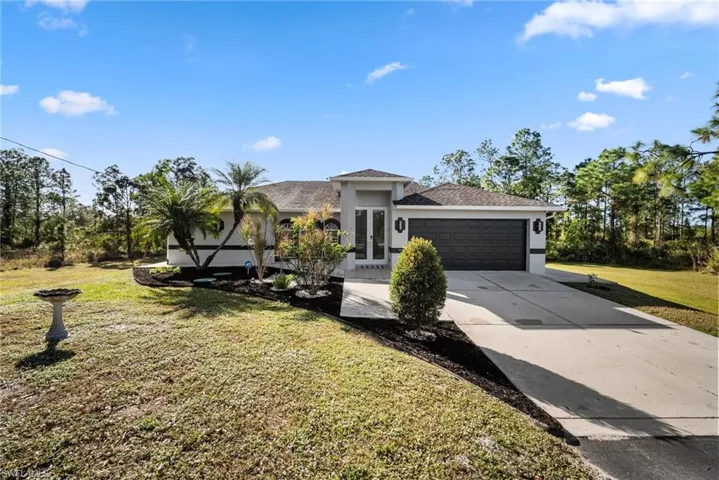 View of front of property featuring a garage, a front yard, and french doors