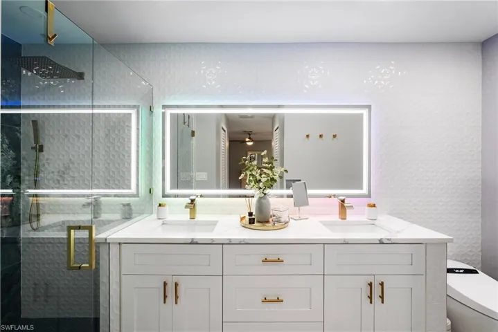 Bathroom featuring ceiling fan, a shower with door, vanity, and toilet