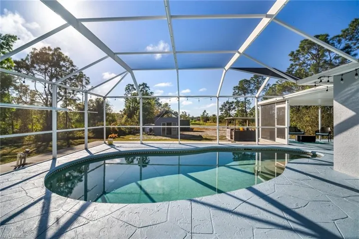 View of pool featuring glass enclosure and a patio area