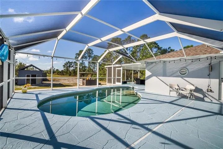 View of pool with a patio area and glass enclosure