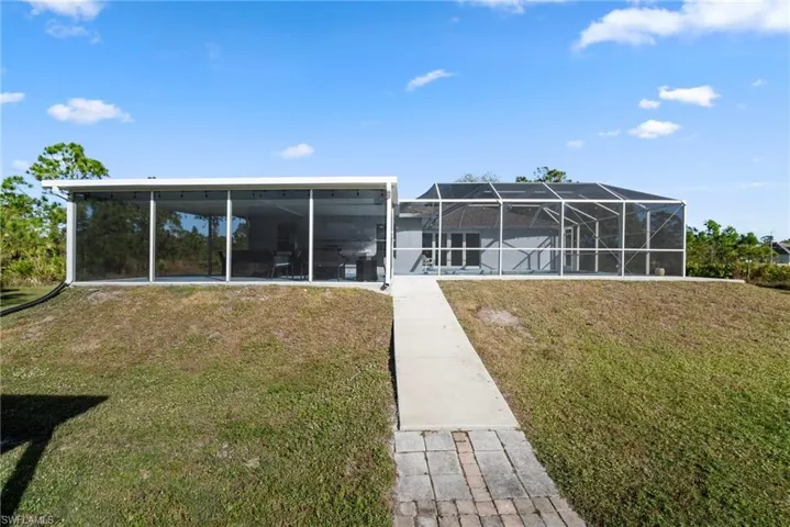 Rear view of house featuring a yard and a lanai