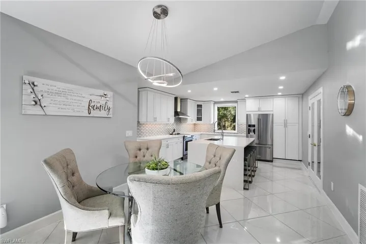 Tiled dining area with vaulted ceiling and sink