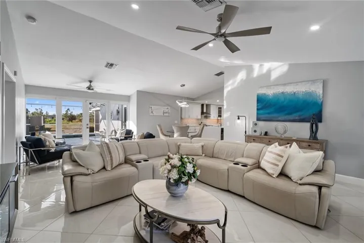 Tiled living room featuring french doors, vaulted ceiling, and ceiling fan