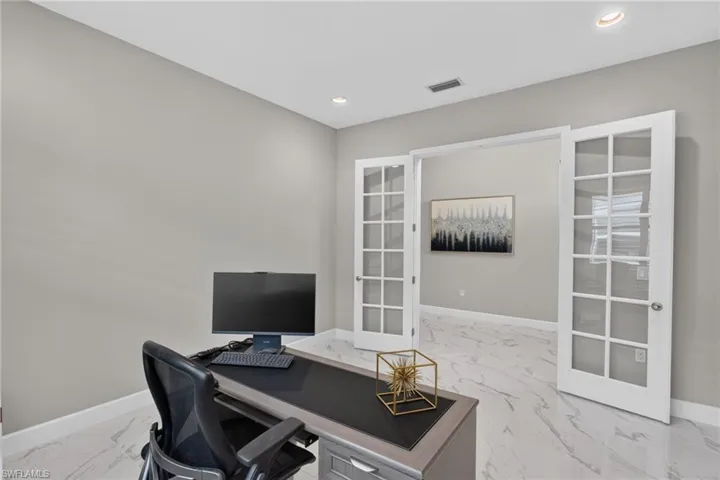 Spacious room featuring light gray walls, recessed lighting, and white baseboards
