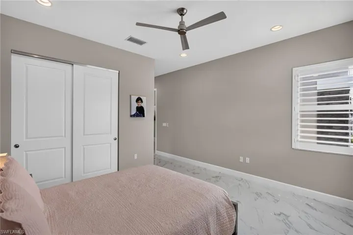 Spacious room featuring white panel sliding closet doors, a contemporary ceiling fan, and recessed lighting