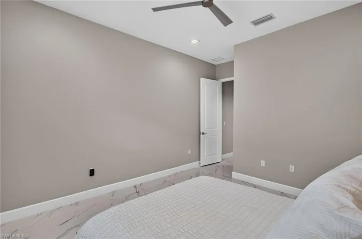 Spacious room featuring light gray walls, large format tile flooring, and a modern ceiling fan