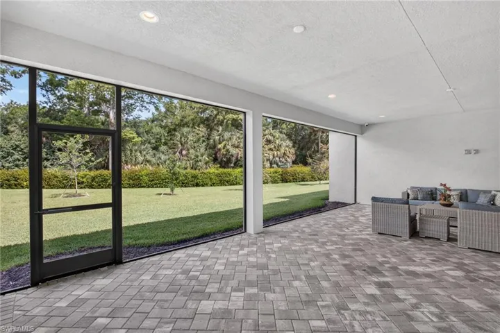 Screened patio featuring gray paver flooring, recessed lighting, and a white stucco wall