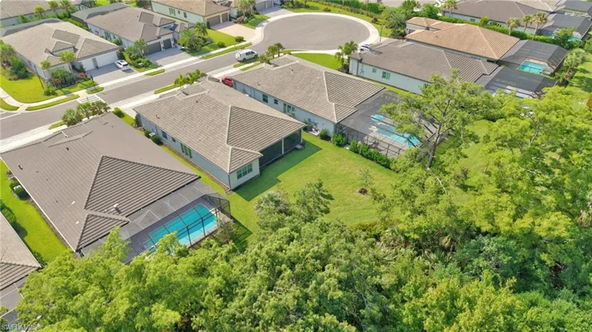 Aerial perspective of a neighborhood featuring houses with screened pools and tiled roofs