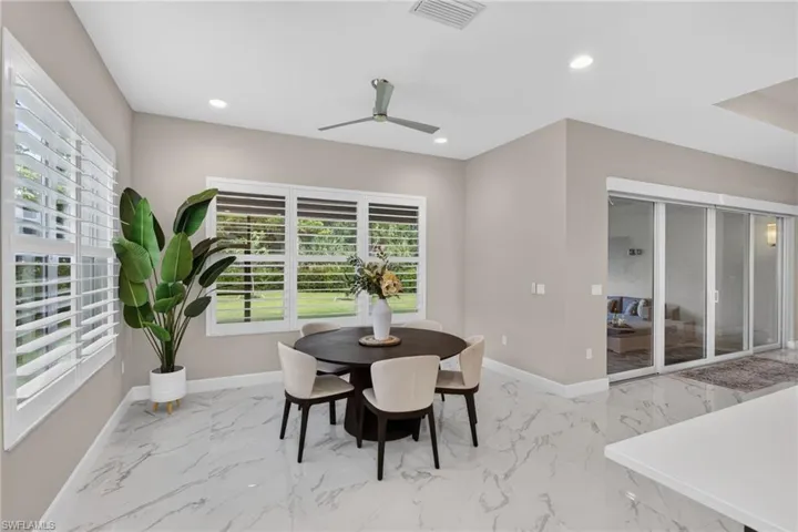 Open-concept dining area featuring large windows with plantation shutters, tile flooring, a contemporary ceiling fan, recessed lighting, and sliding glass doors
