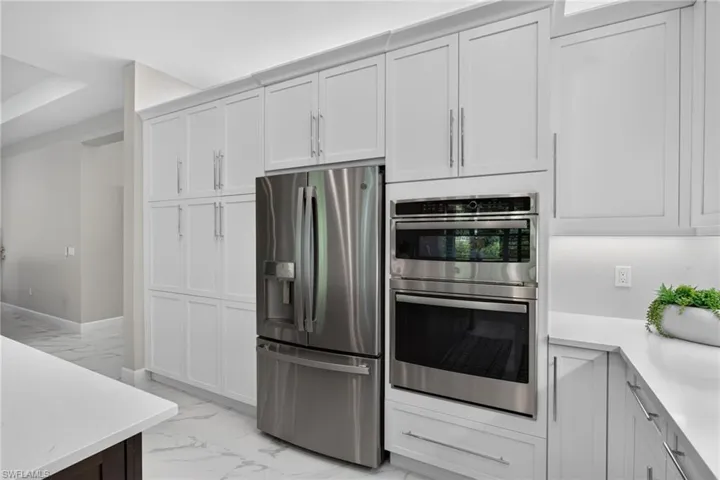 Kitchen featuring extensive white cabinetry with crown molding, stainless steel French door refrigerator, and a built-in double oven