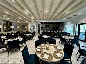 Spacious dining area featuring a coffered ceiling, multiple seating arrangements, a built-in bar, and exterior access
