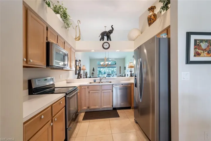 Kitchen with decorative light fixtures, kitchen peninsula, stainless steel appliances, sink, and light tile floors