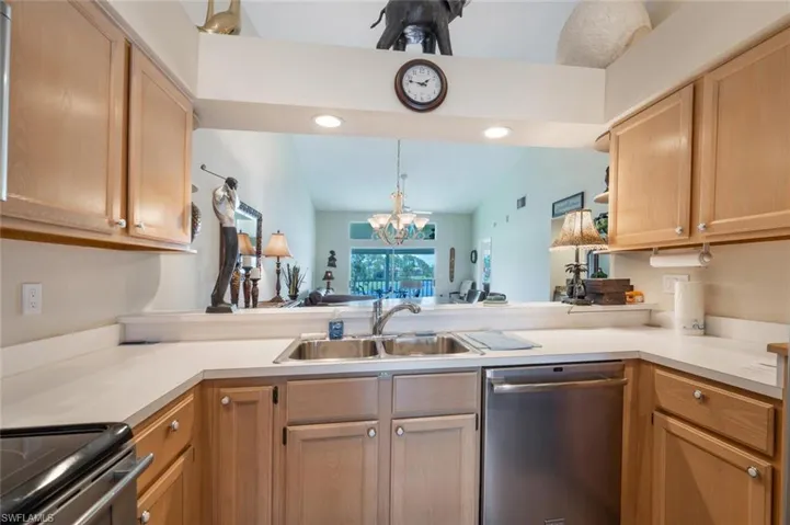 Kitchen with lofted ceiling, kitchen peninsula, a notable chandelier, sink, and dishwasher