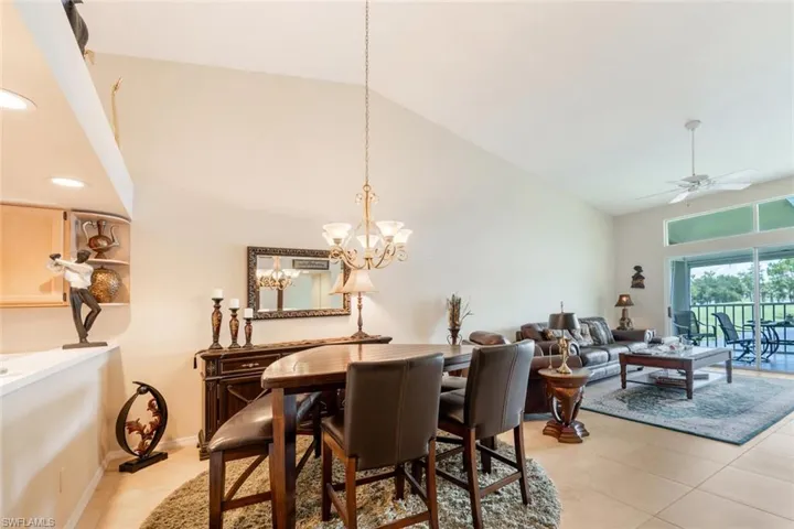 Dining room with high vaulted ceiling, light tile flooring, and ceiling fan with notable chandelier