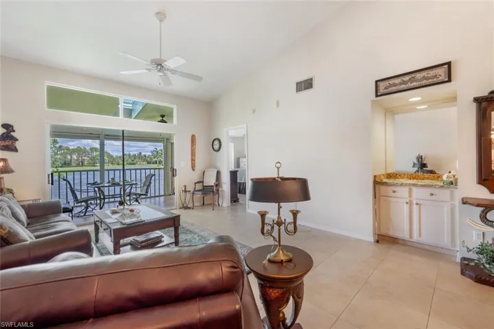 Living room with high vaulted ceiling, ceiling fan, and light tile floors