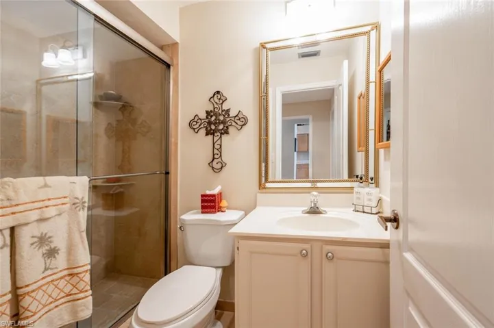 Bathroom featuring a shower with shower door, toilet, and vanity with extensive cabinet space