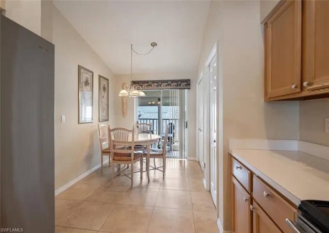 Kitchen featuring vaulted ceiling, a chandelier, range, light tile floors, and pendant lighting