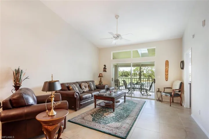 Living room with high vaulted ceiling, ceiling fan, and light tile flooring