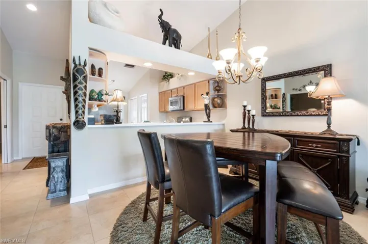 Tiled dining area featuring high vaulted ceiling and a chandelier