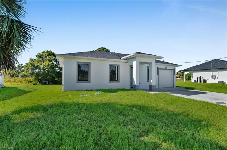 View of front of home featuring a front yard, concrete driveway, stucco siding, and an attached garage