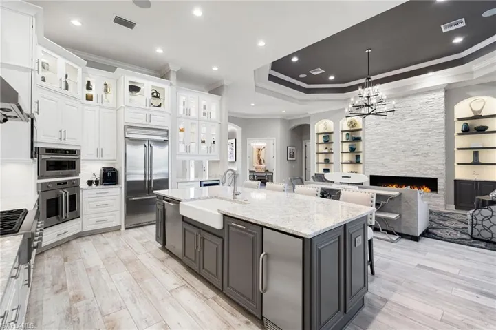 Kitchen featuring a kitchen bar, built in shelves, a stone fireplace, arched walkways, and ornamental molding