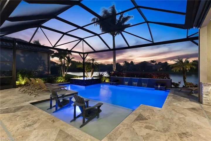 View of swimming pool with glass enclosure, a patio area, a sunroom, a pool with connected hot tub, and a water view