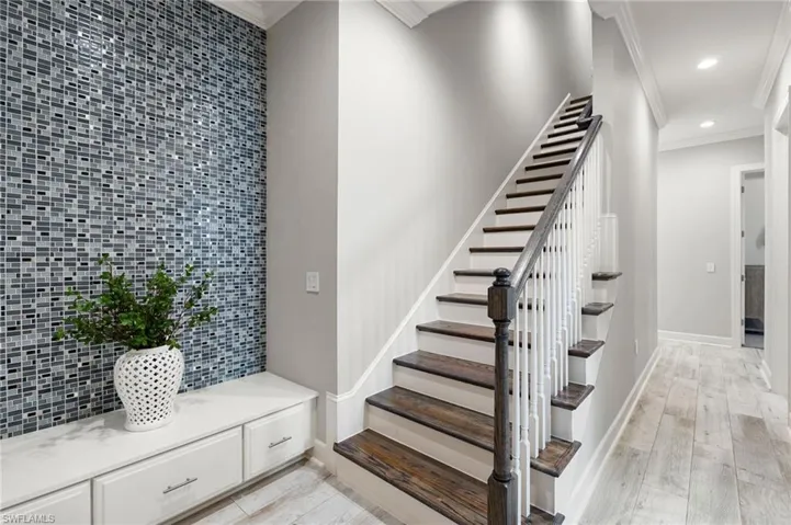 Stairway with crown molding, recessed lighting, and wood finished floors