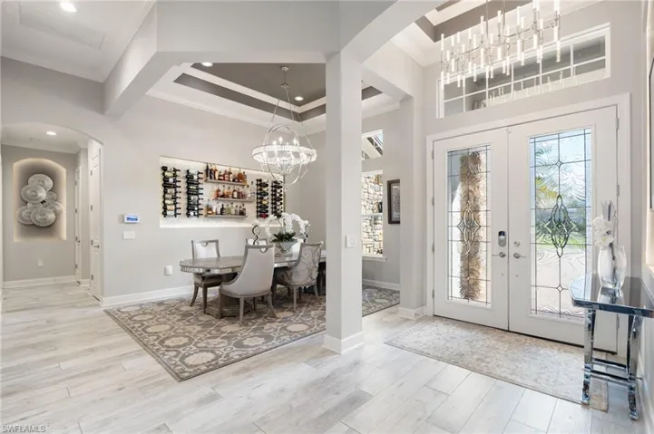 Foyer featuring a chandelier, arched walkways, french doors, ornamental molding, and light wood finished floors