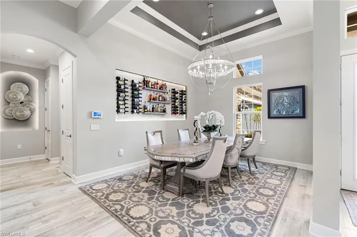 Dining area with ornamental molding, recessed lighting, light wood-type flooring, arched walkways, and a chandelier