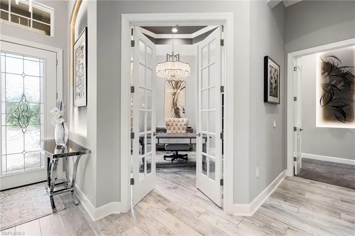 Foyer entrance featuring french doors, a chandelier, light wood-style floors, and ornamental molding
