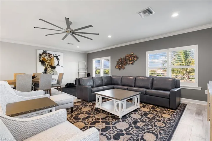 Living area featuring ornamental molding, light wood-type flooring, a ceiling fan, and recessed lighting
