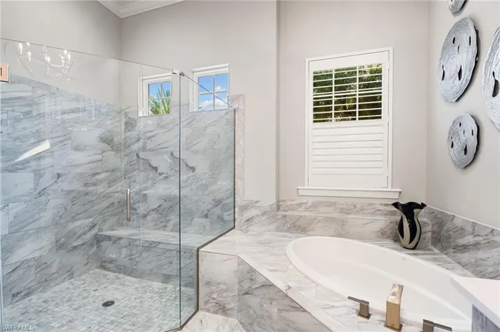 Bathroom with a bath, a marble finish shower, and ornamental molding