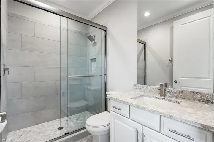 Full bath featuring crown molding, vanity, a shower stall, and recessed lighting
