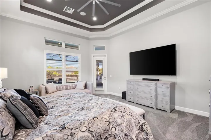 Bedroom featuring crown molding, light carpet, a ceiling fan, access to exterior, and a towering ceiling