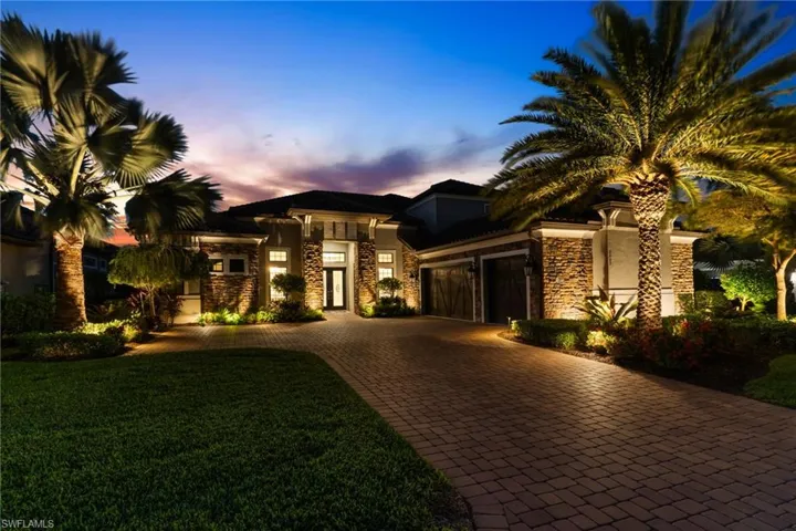 View of front facade featuring stone siding, decorative driveway, a garage, stucco siding, and a yard