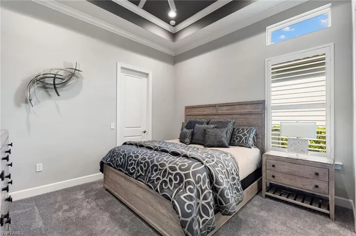 Carpeted bedroom with multiple windows and ornamental molding