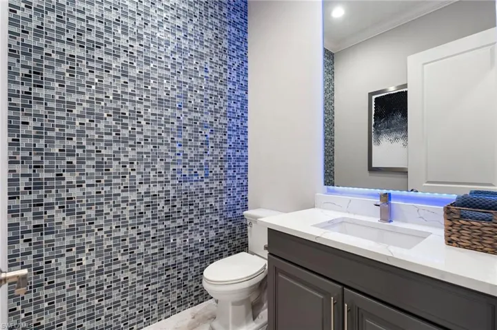 Half bathroom featuring vanity, ornamental molding, and recessed lighting