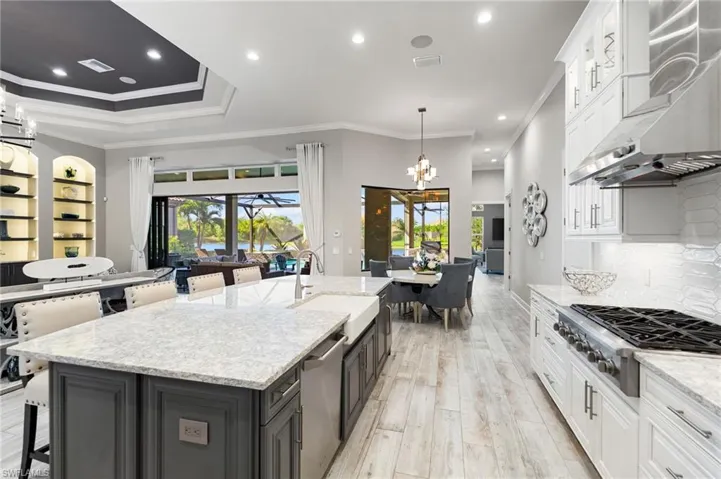 Kitchen featuring white cabinetry, a breakfast bar area, light stone counters, ornamental molding, and recessed lighting