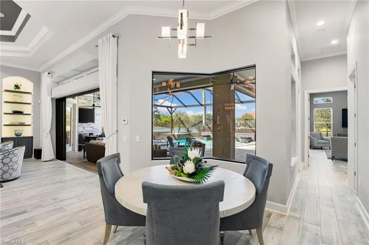 Dining room with a sunroom, ornamental molding, light wood-type flooring, and recessed lighting
